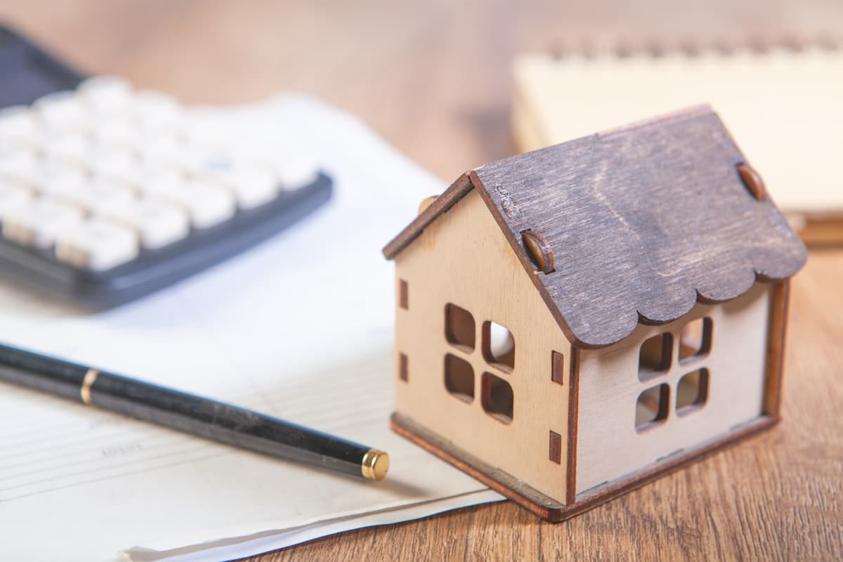 A model house beside a calculator and finances